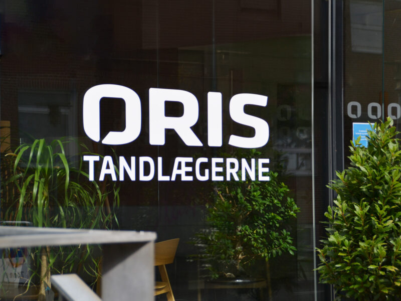 Oris Tandlægernes logo udskåret i folie på facadevindue